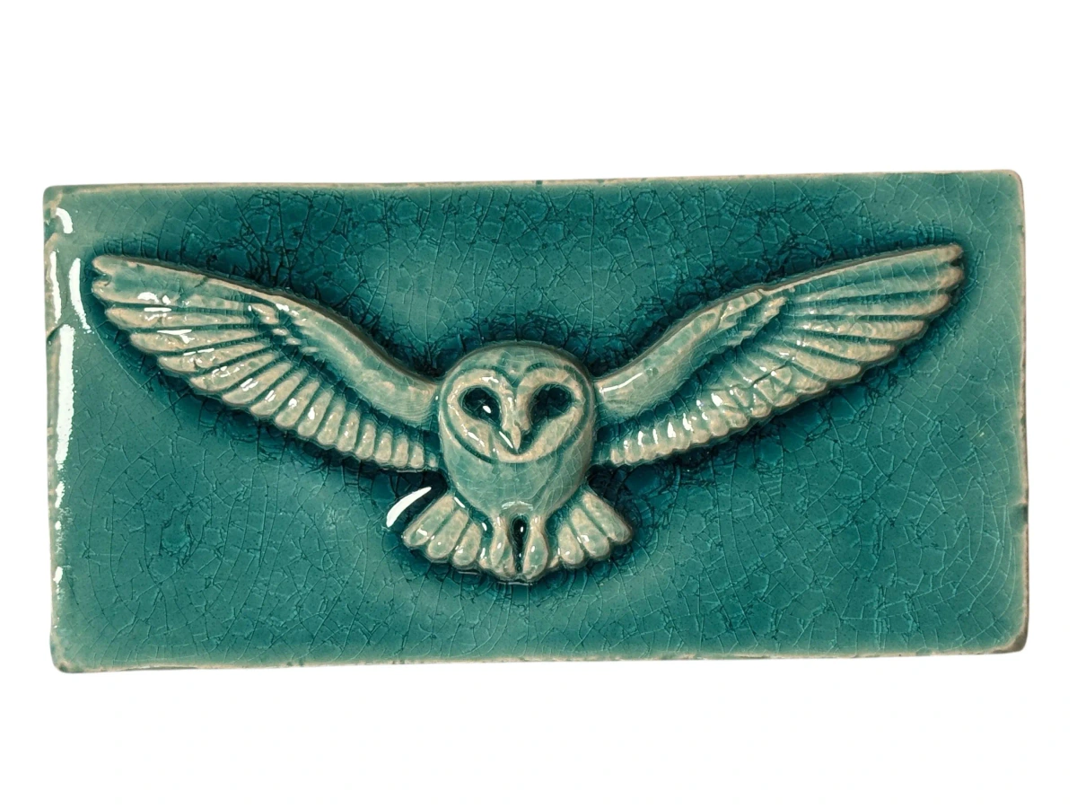 Längliche türkis glasierte Relief-Fliese mit einer Eule und weit ausgebreiteten Flügeln