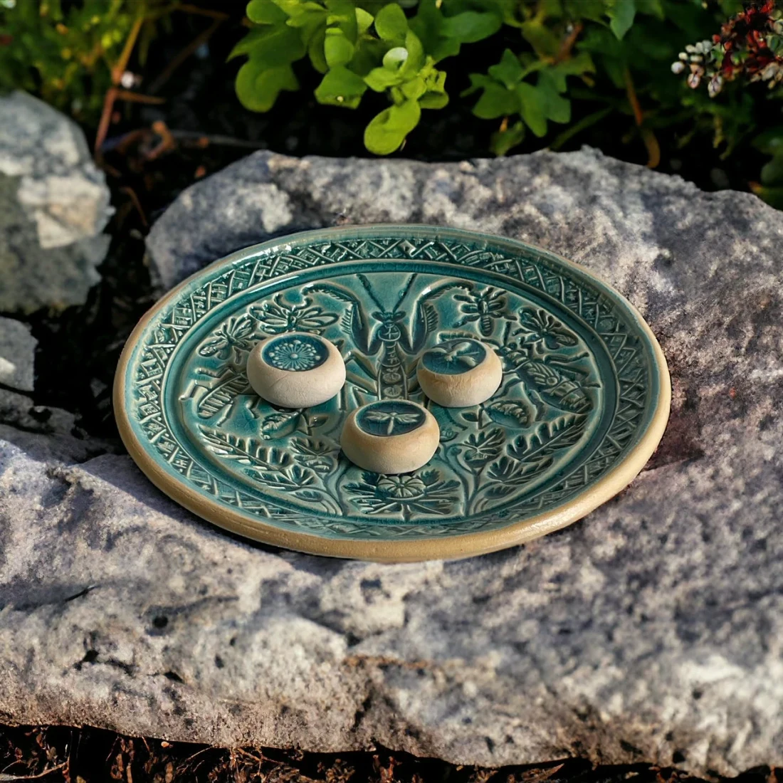 Türkise Mantis-Tränke mit drei Keramiksteinen auf einem Felsen im Garten