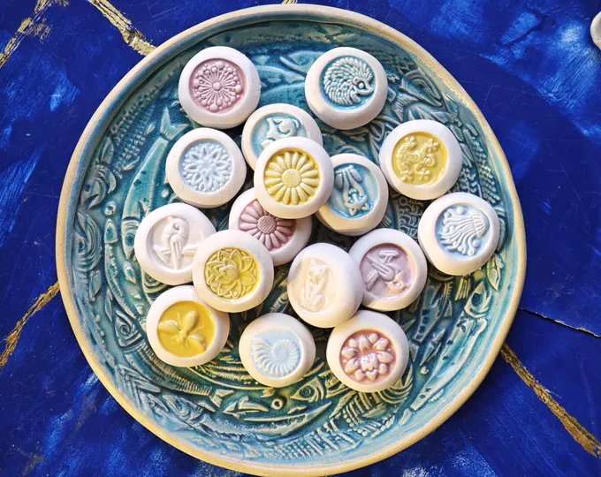 Keramiksteine mit unterschiedlich pastellfarben glasierten Motiven